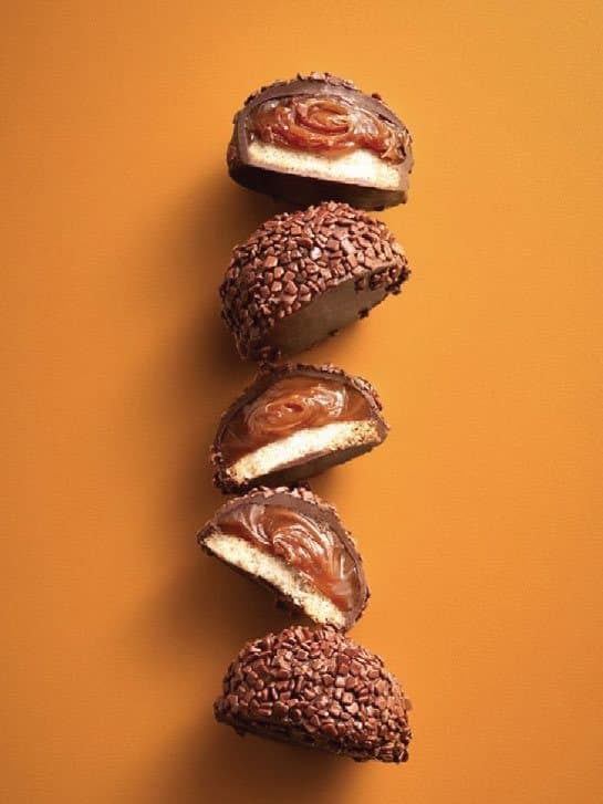 Five bonbons arranged vertically on a turmeric-orange background